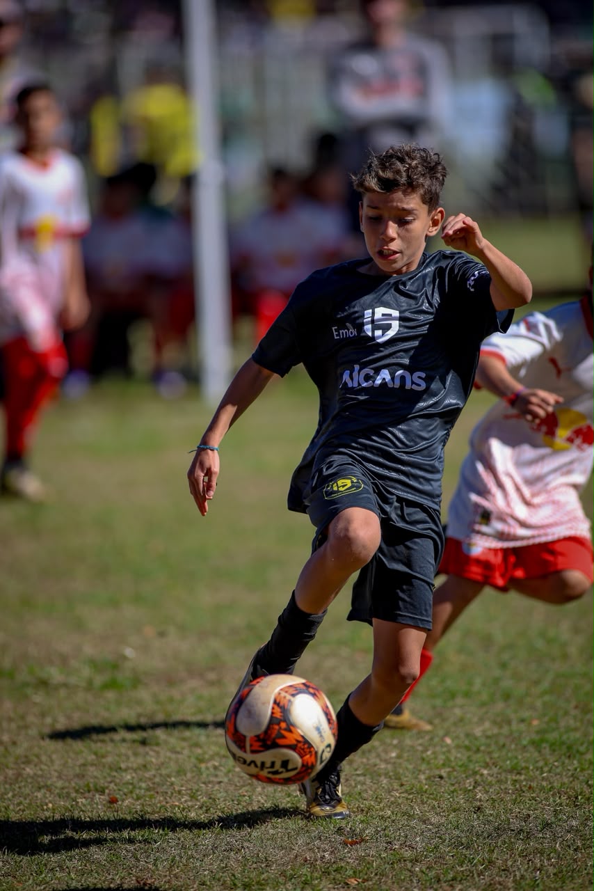 Isaac conduz a bola durante a partida, com uniforme preto